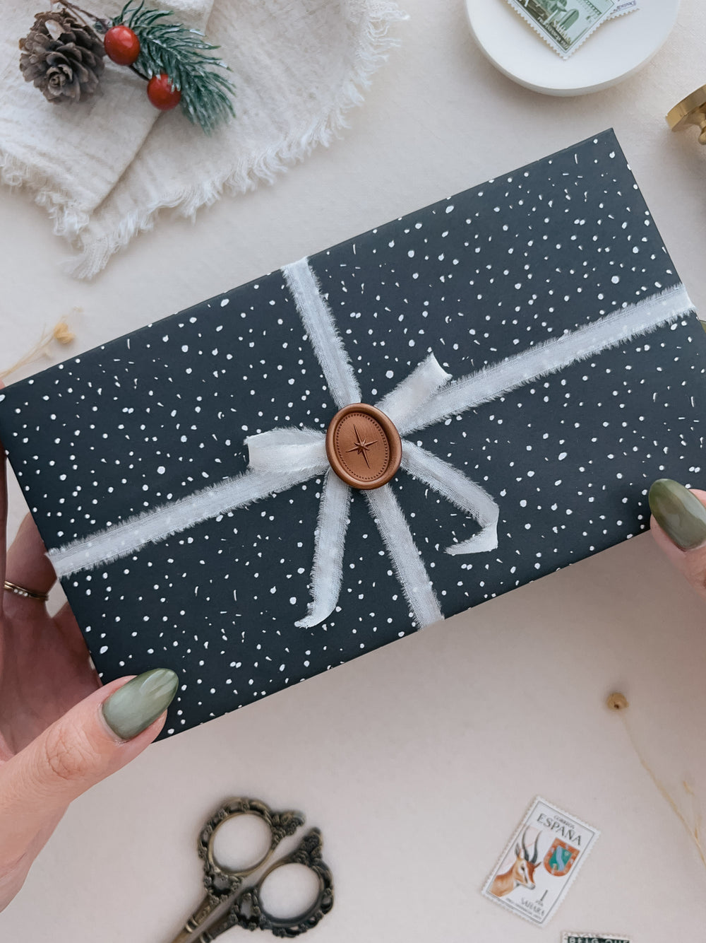 Copper bronze colored North Star mini oval wax seal on a wrapped Christmas gift