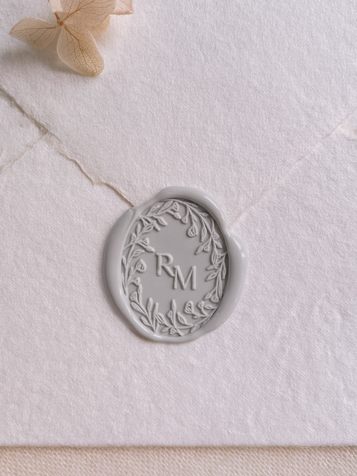 Oval floral crown monogram wax seal in light gray on white handmade paper envelope