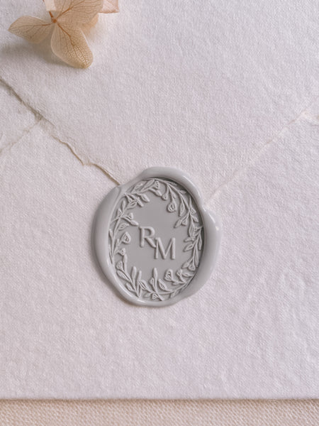 Oval floral crown monogram wax seal in light gray on white handmade paper envelope