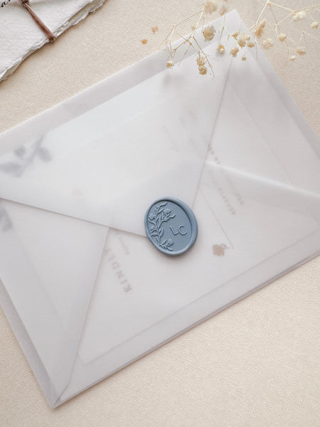 Oval floral silhouette design monogram wax seal in color dusty blue on a vellum envelope