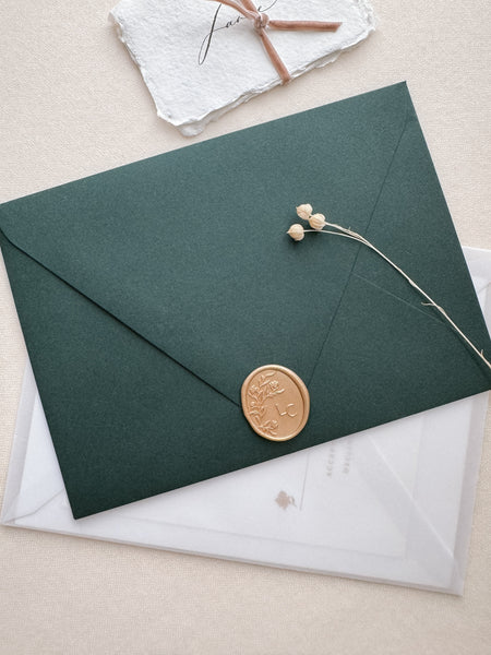 Oval floral monogram custom wax seals in color light gold on a dark green envelope