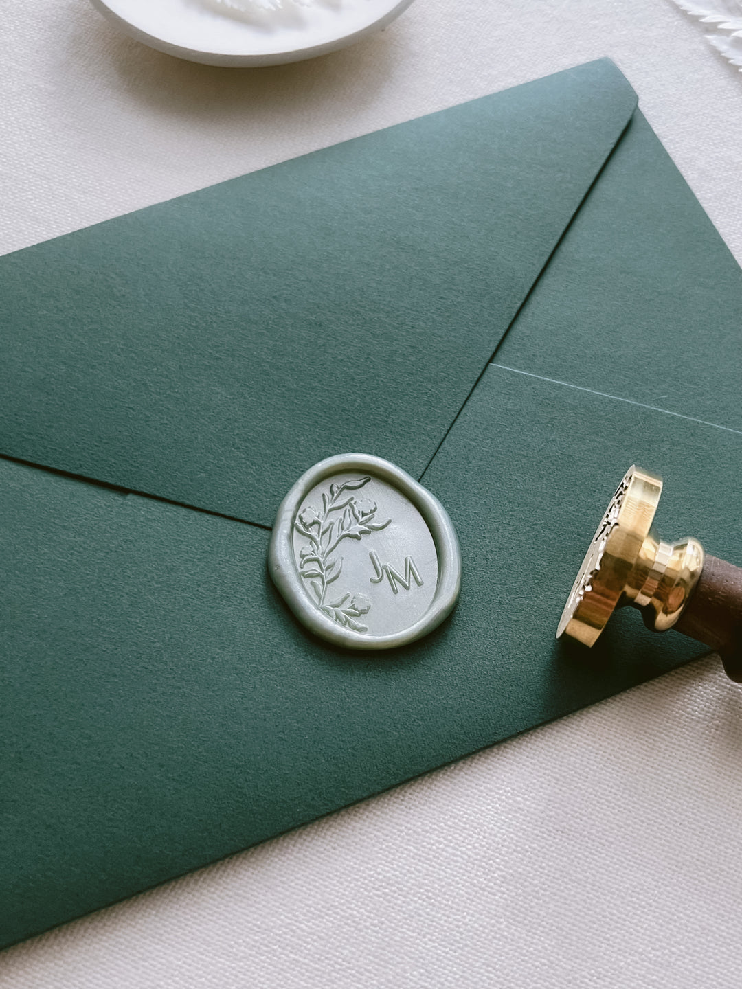Metallic green personalized floral monogram oval wax seal on a green envelope 
