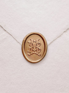 Oval vintage monogram gold wax seal on a white handmade paper envelope