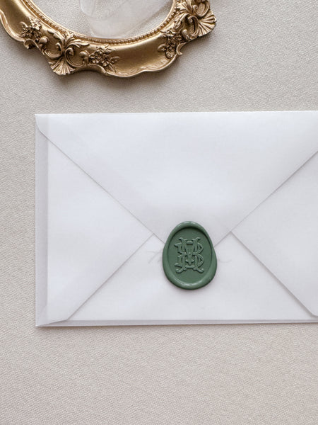 Oval vintage monogram green wax seal on a vellum envelope