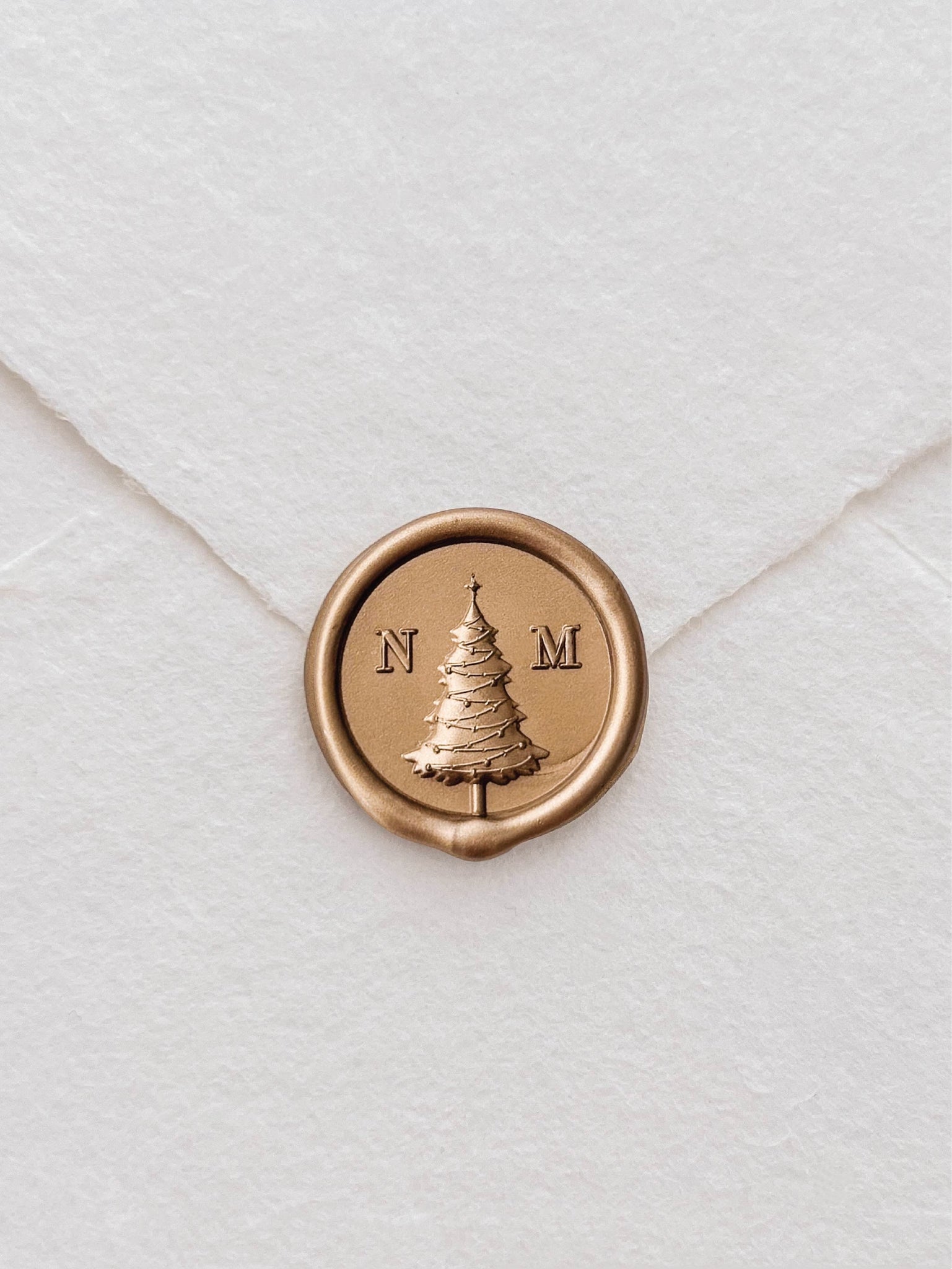 Personalized monogram gold wax seal with a Christmas tree design in the center and a custom initial on each side