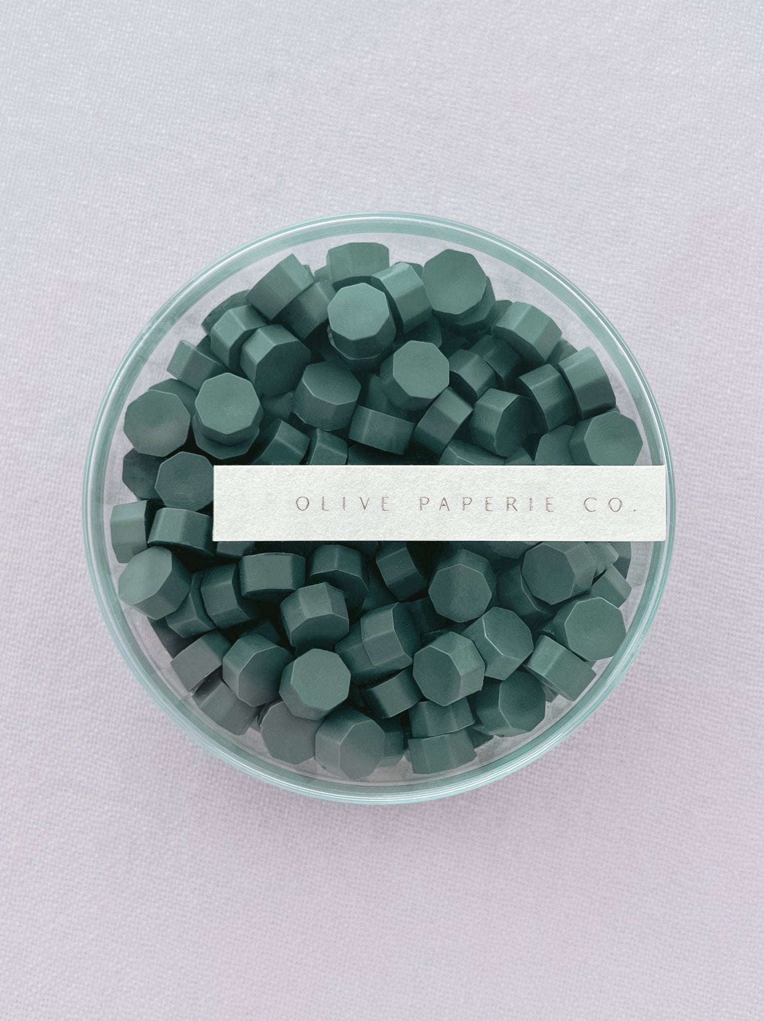 non-metallic pine green sealing wax beads in a clear round box