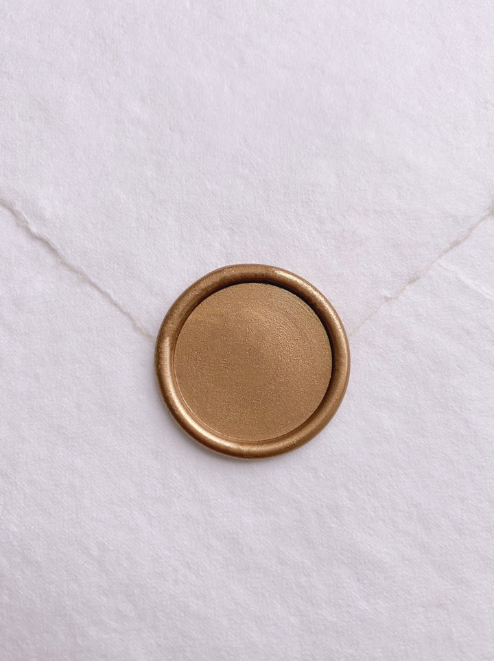 Round blank gold wax seal on white handmade paper envelope