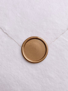Round blank gold wax seal on white handmade paper envelope