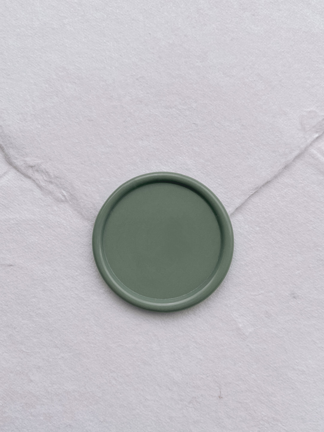 Sage green blank wax seal on white handmade paper envelope