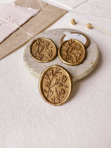Oval floral gold wax seals with 3D engraving styled with a small gray stone dish, handmade paper and a dried floral branch