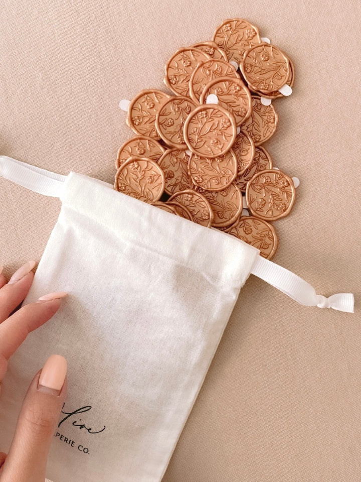 Peachy gold colored floral wax seals with 3D engraving with 3M stickers in a white linen pouch