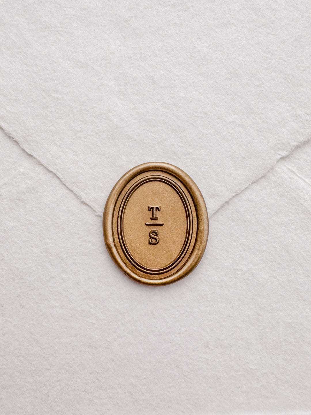 Personalized initials gold oval border wax seal featuring a custom monogram with a double line border design on a white textured envelope