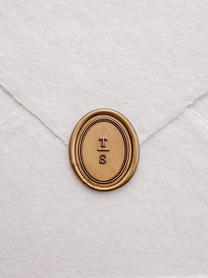 Personalized initials gold oval border wax seal featuring a custom monogram with a double line border design on a white textured envelope