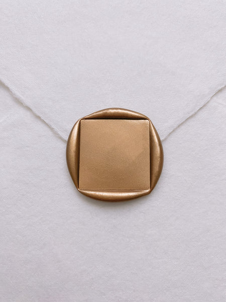 Square blank gold wax seal on white handmade paper envelope