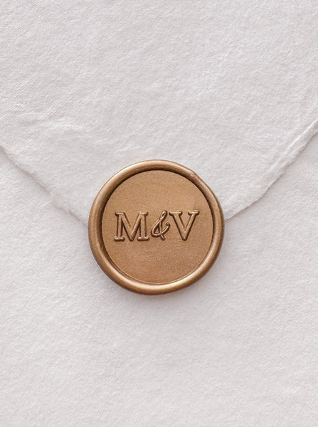 Typeface monogram gold wax seal on a white handmade paper envelope