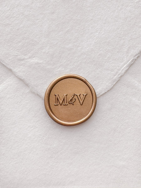 Typeface monogram gold wax seal on white handmade paper envelope