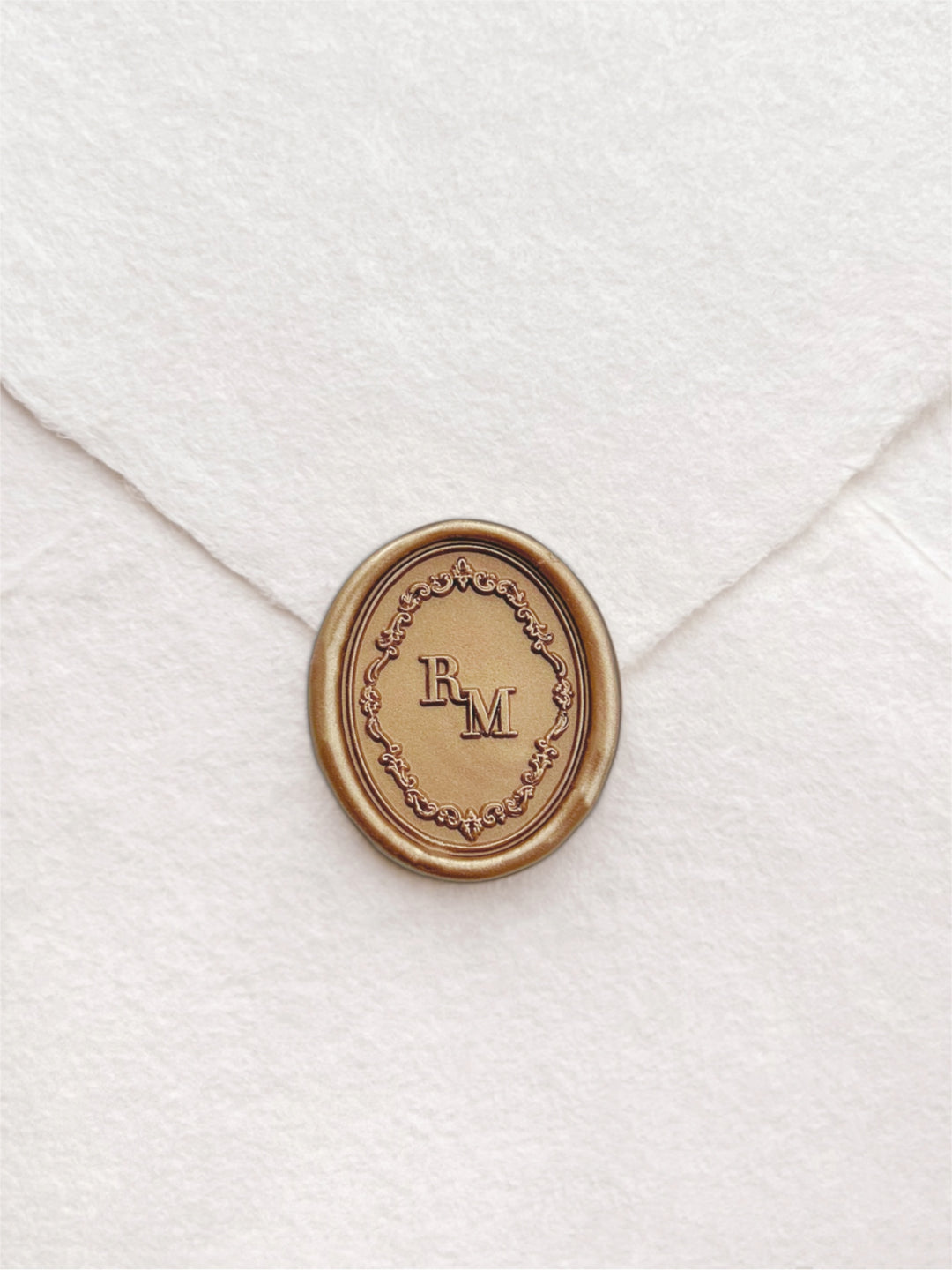 Gold custom monogram oval vintage ornate frame wax seal on a white deckled edge handmade paper envelope
