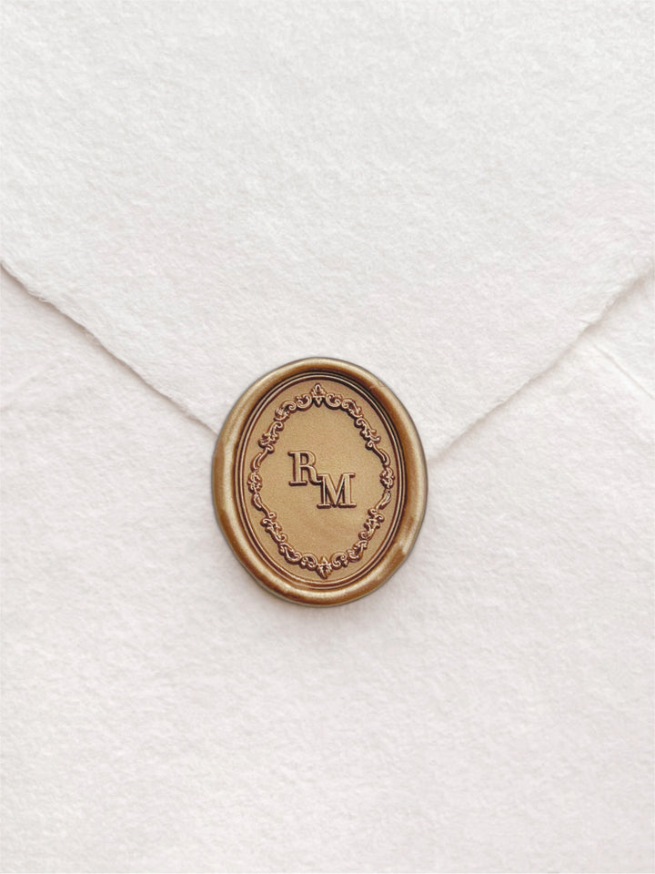Gold custom monogram oval vintage ornate frame wax seal on a white deckled edge handmade paper envelope