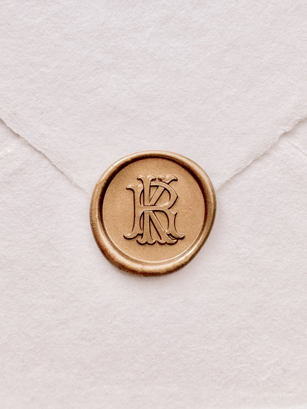gold vintage monogram wax seal on a white envelope