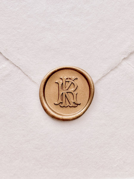 gold vintage monogram wax seal on a white envelope