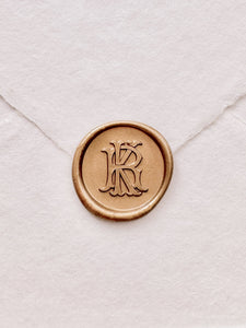 Gold vintage monogram wax seal on a white handmade paper envelope