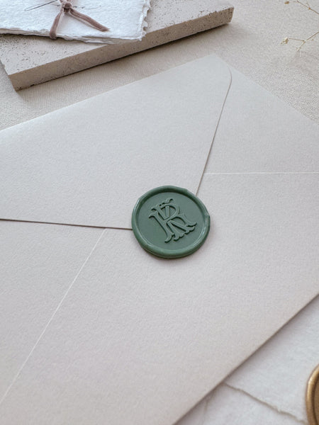 Green vintage monogram wax seal on a beige envelope