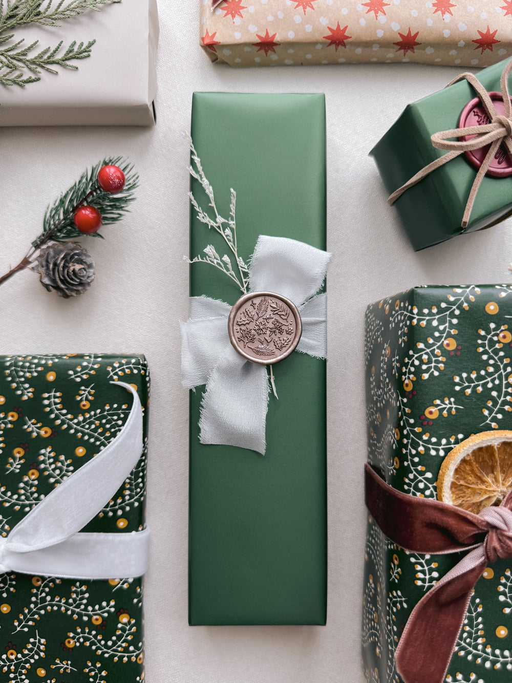 Light bronze winter garden floral and botanical elements wax seal on a wrapped Christmas gift