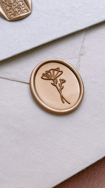 Gold bstract floral oval wax seal on white envelope