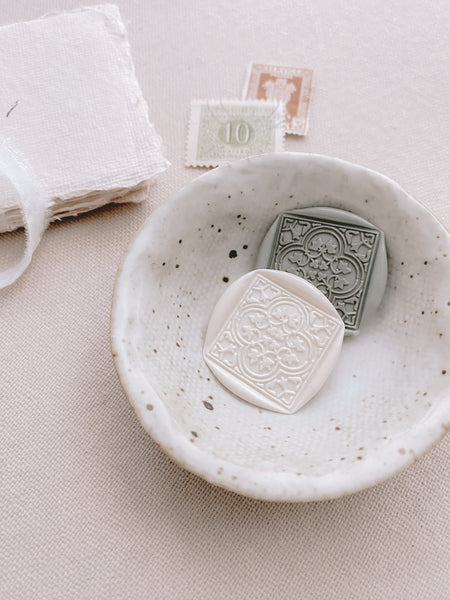 Moroccan tile quatrefoil pattern wax seals in off white and sage green in small bowl