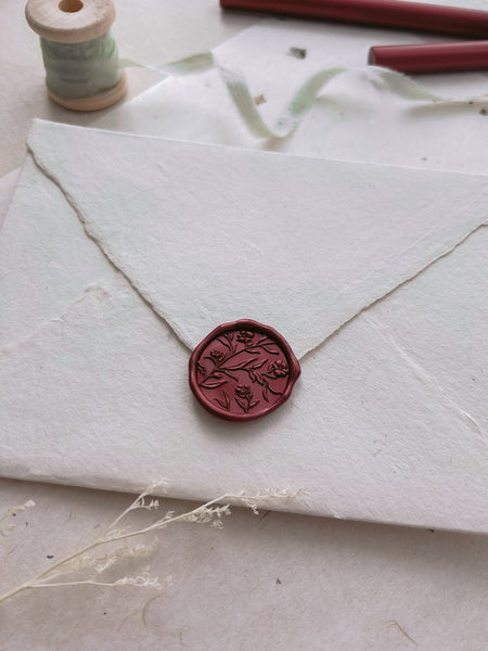 Vintage-style red wax seal with floral design on a letter envelope