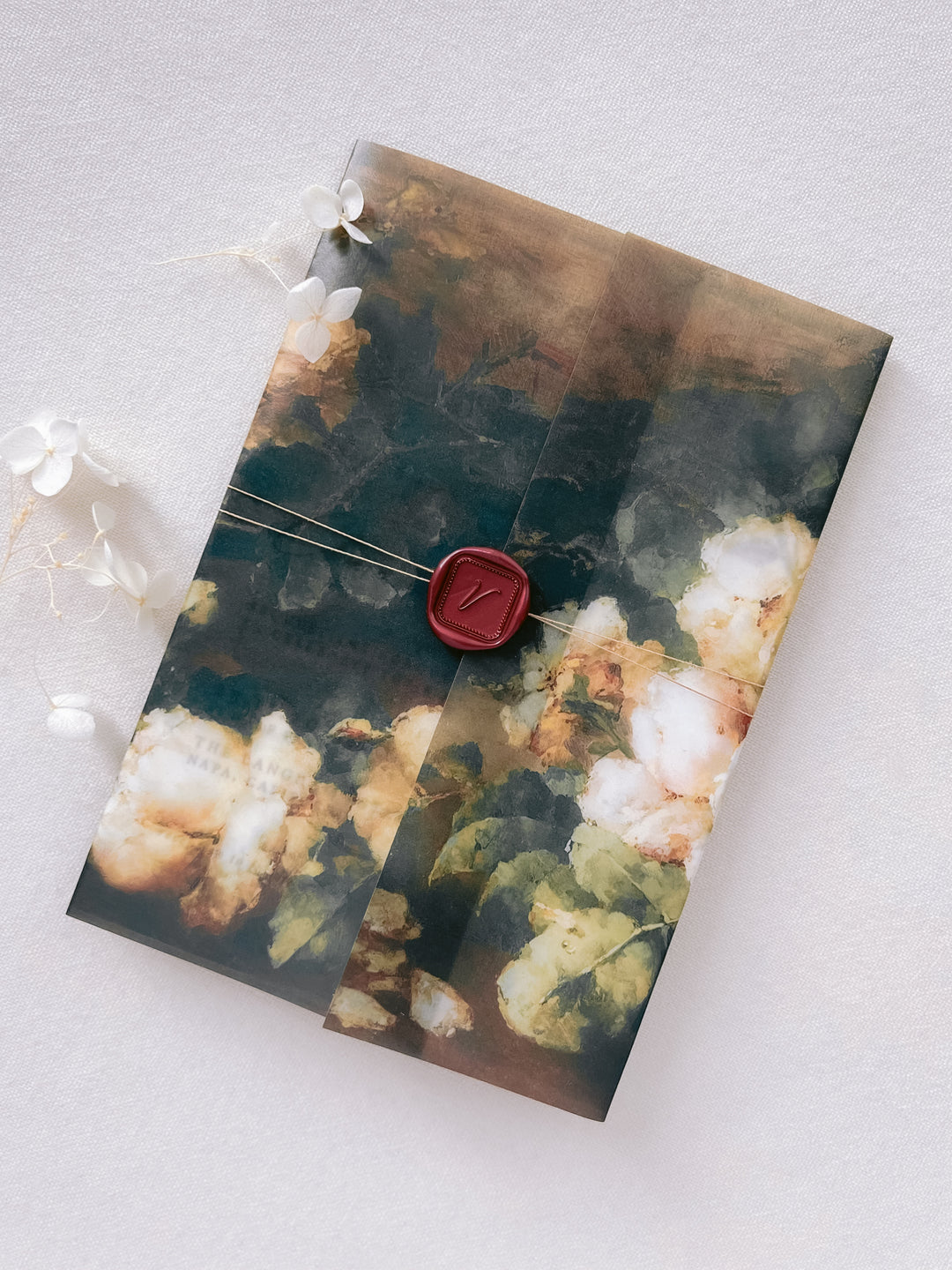 Custom initial wax seal in antique red, on a delicate wedding invitation floral vellum jacket