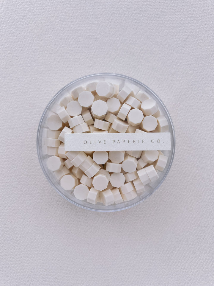 Warm off-white sealing wax beads in a clear container box