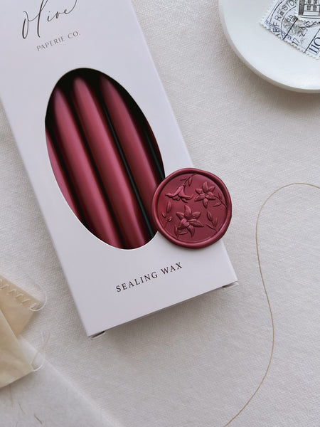 dark metallic red lilies floral wax seal on a box of metallic red sealing wax sticks