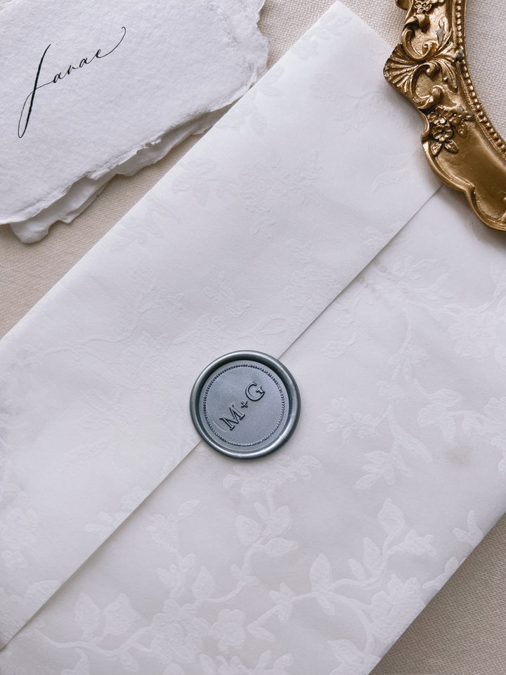 Silver personalized initials border wax seal featuring a custom monogram on a white floral print envelope wrap 