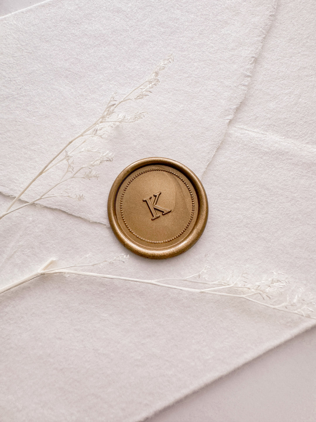 Gold personalized initial border design wax seal featuring a custom monogram on a white deckled edge handmade paper envelope
