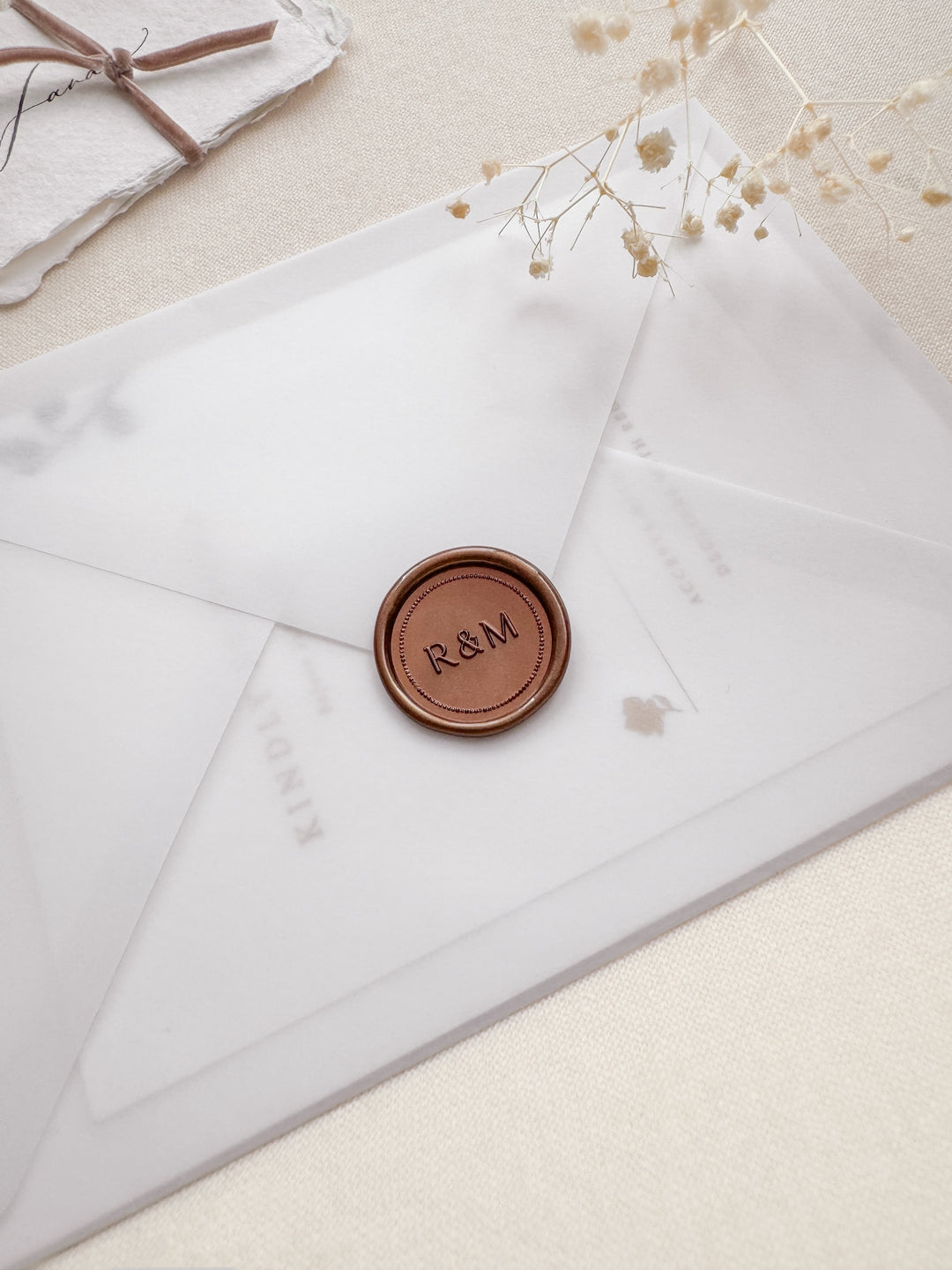 Bronze personalized initials dot border wax seal featuring a custom monogram on a vellum wedding invitation envelope 