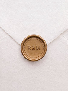 Gold monogram wax seal with a dotted border design