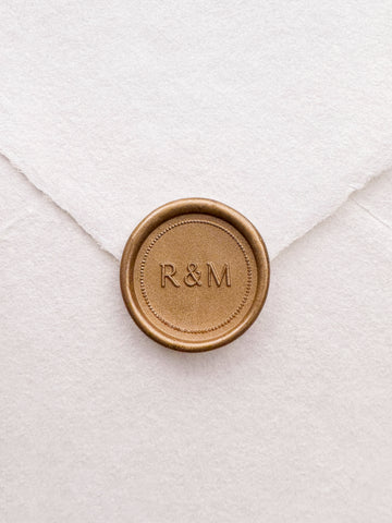 Gold monogram wax seal with a dotted border design