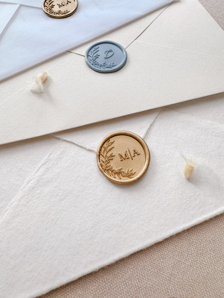 Custom monogram leaf wreath wax seals in color dusty blue, light gold, and classic ogld