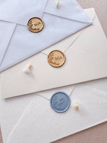 Custom monogram leaf wreath wax seals in color dusty blue, light gold, and classic ogld