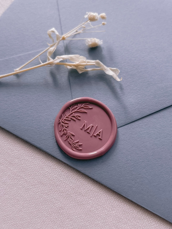 rose colored botanical custom initials wax seal on a dusty blue envelope 