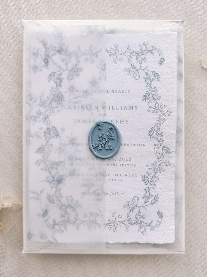 Dusty blue botanical vine wax seal on a vellum overlay, layered over a hand-illustrated floral wedding invitation card.