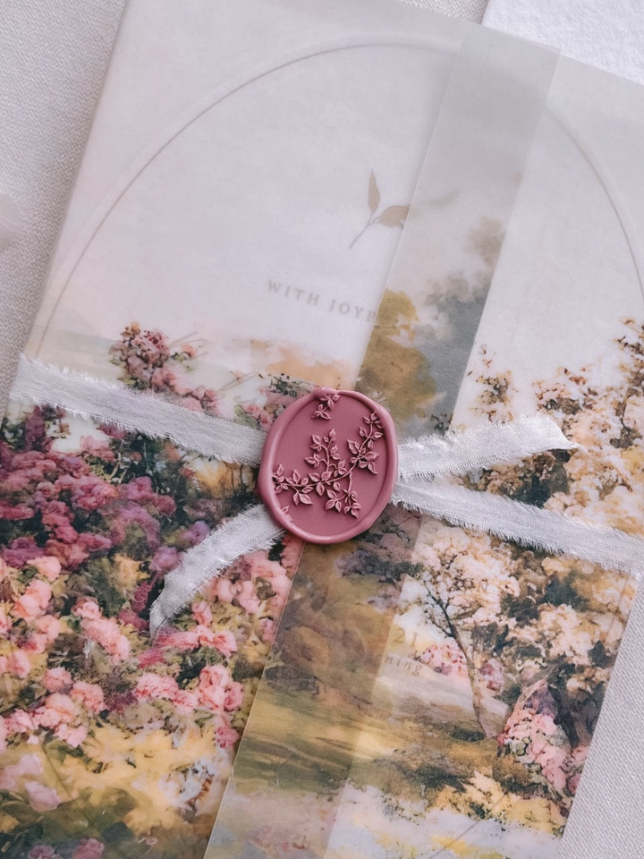Mauve pink botanical vine wax seal securing a ribbon-tied watercolor garden print vellum overlay on a wedding invitation card