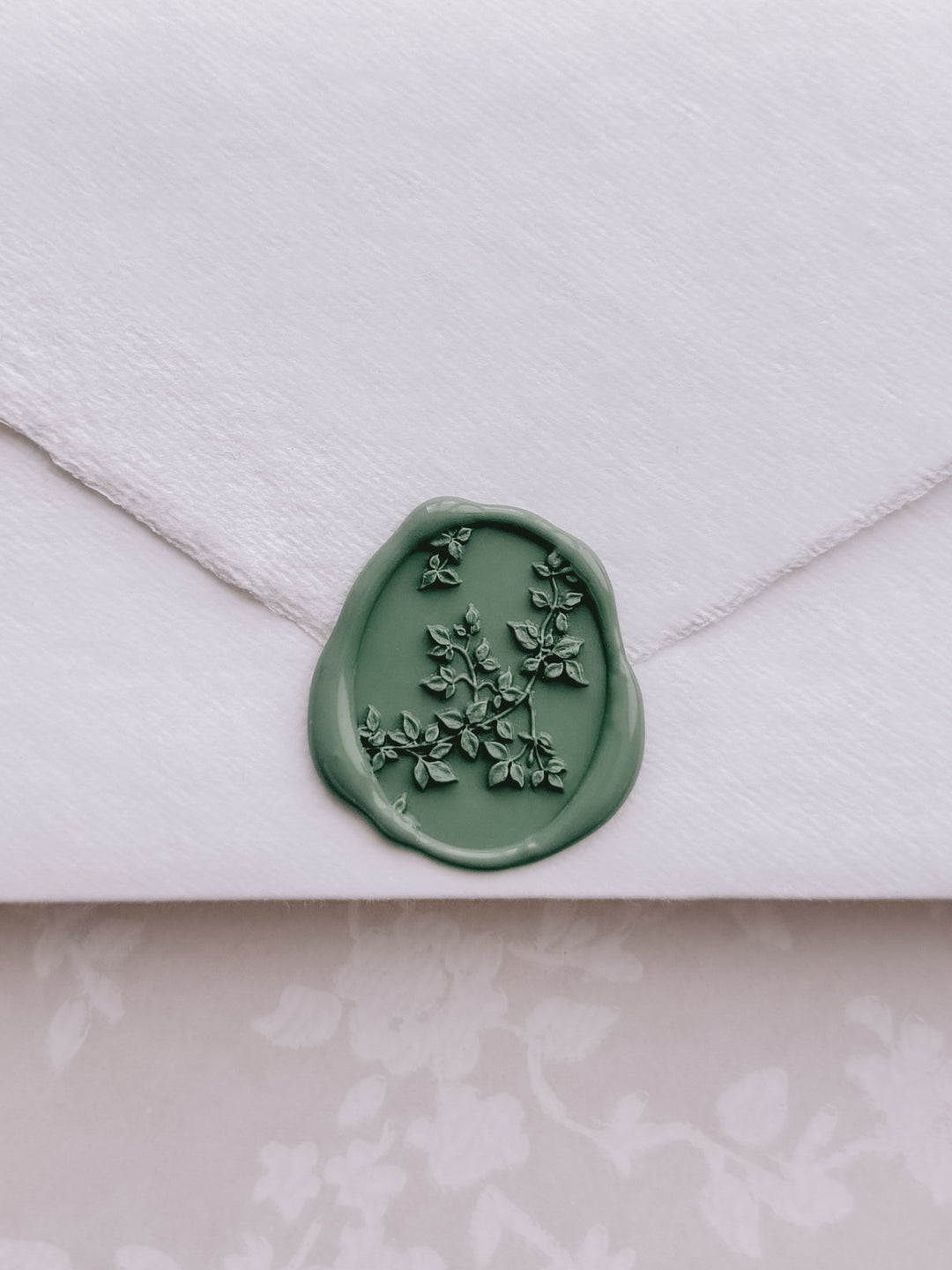 Green botanical vine oval wax seal on a white deckled edge handmade paper envelope