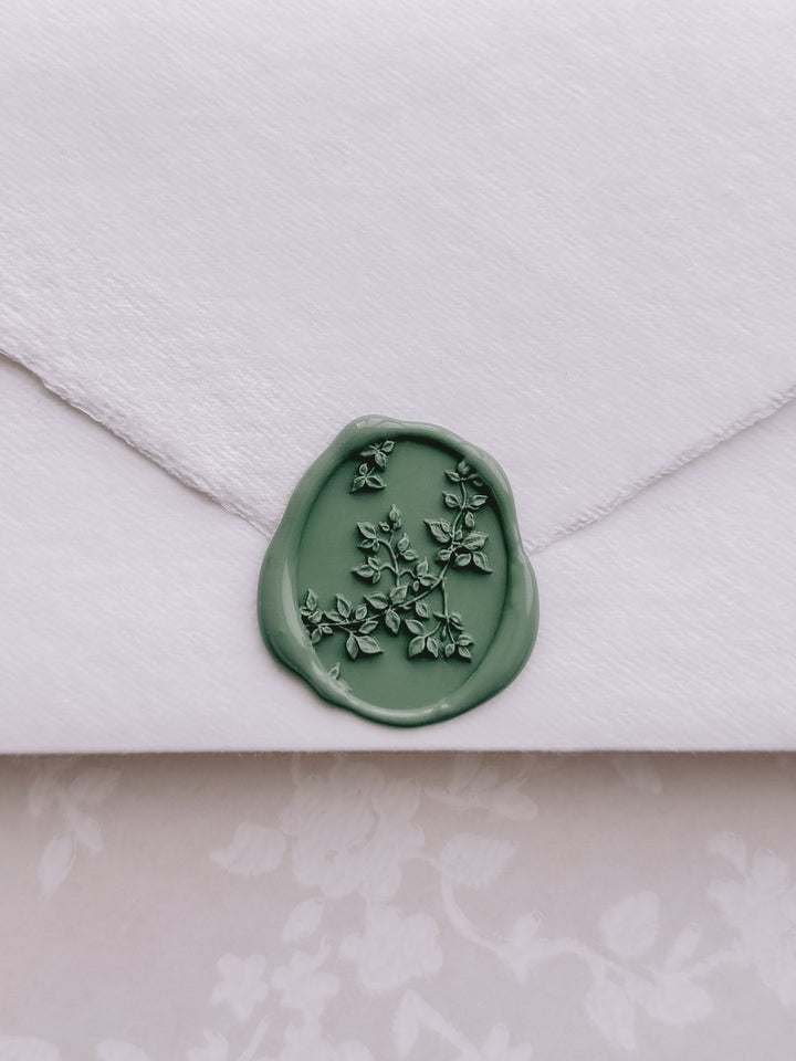 Green botanical vine oval wax seal on a white deckled edge handmade paper envelope
