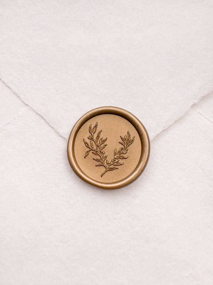 Delicate botanical gold wax seal on a white handmade paper envelope