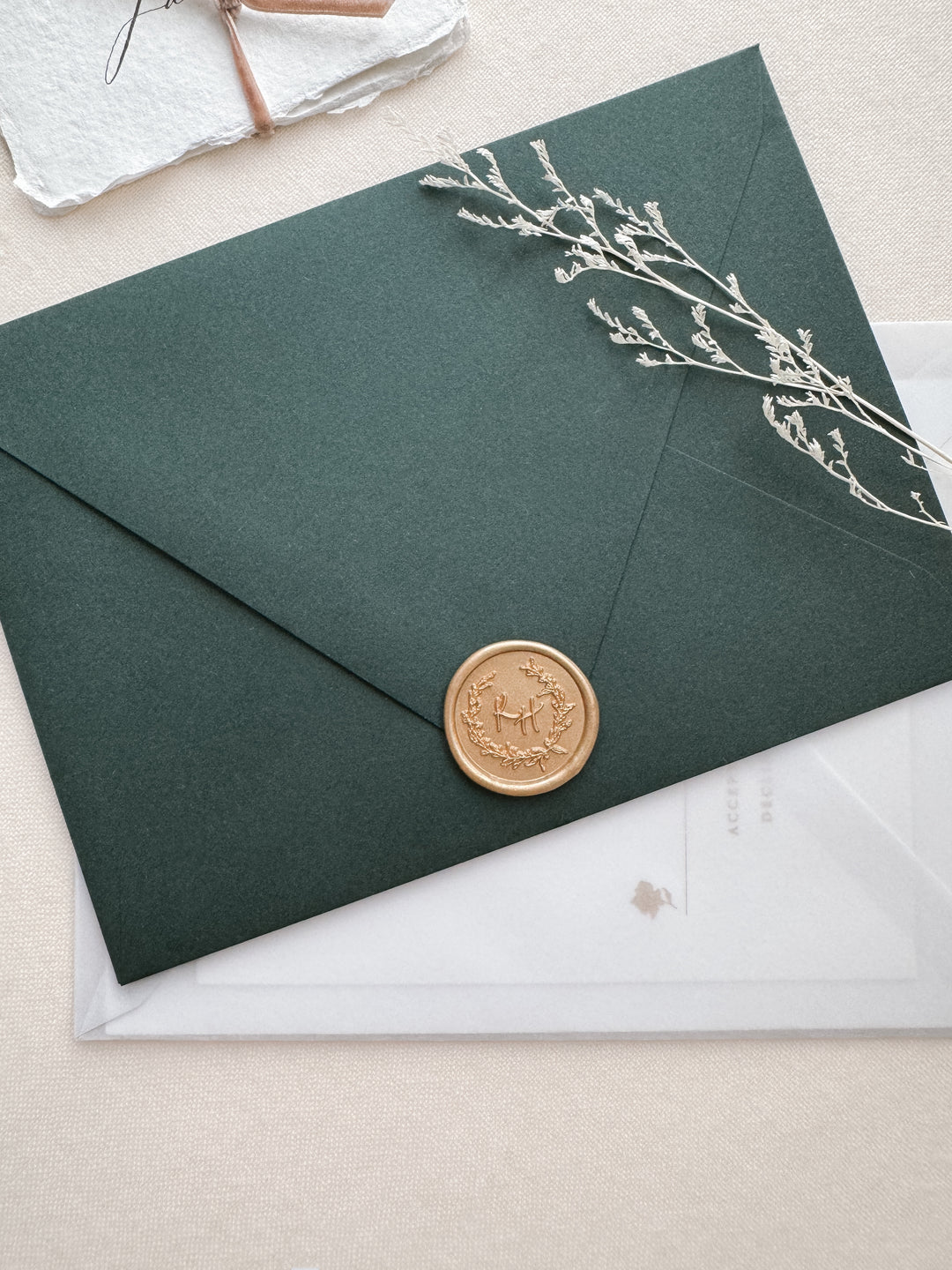 light gold personalized botanical wreath custom initials wax seal on a dark green envelope