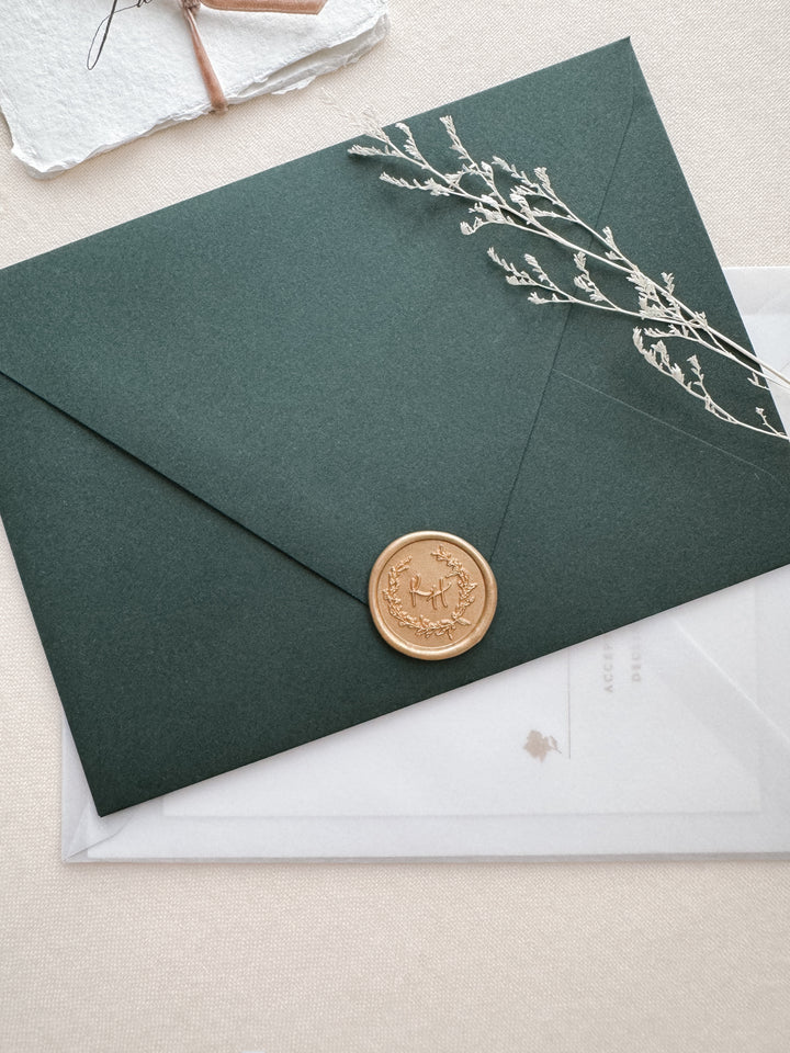light gold personalized botanical wreath custom initials wax seal on a dark green envelope