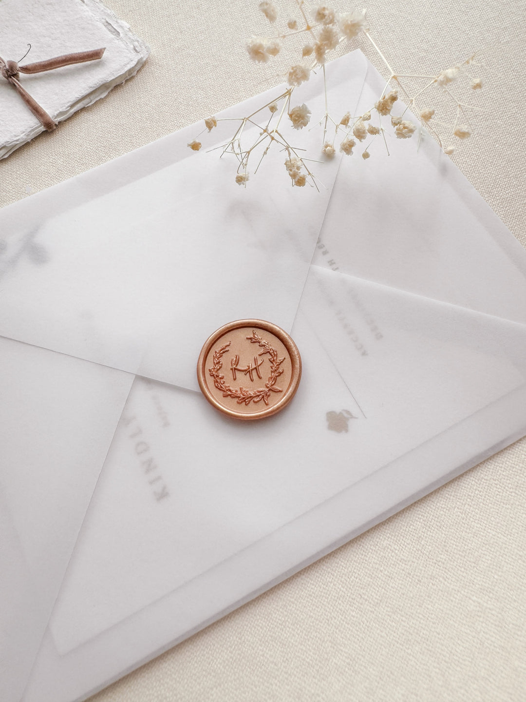 peachy gold custom monogram wax seal with a floral wreath design on a wedding invitation envelope