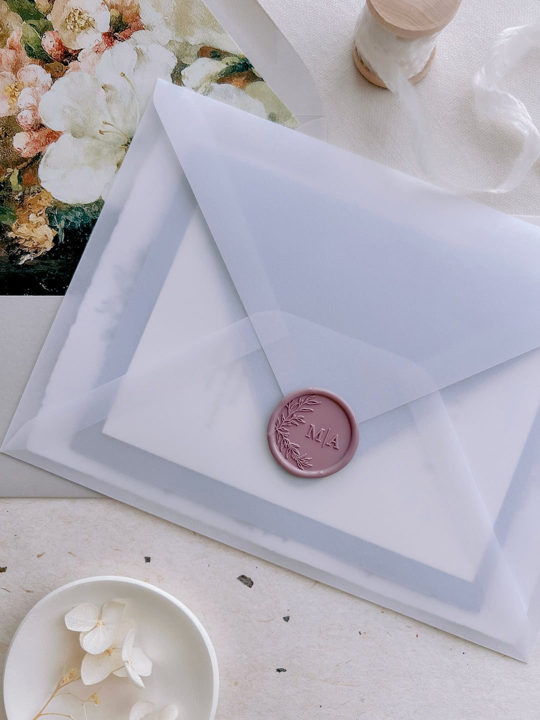 Mauve colored botanical wreath custom wax seal with personalized initials, on a vellum wedding invitation envelope 
